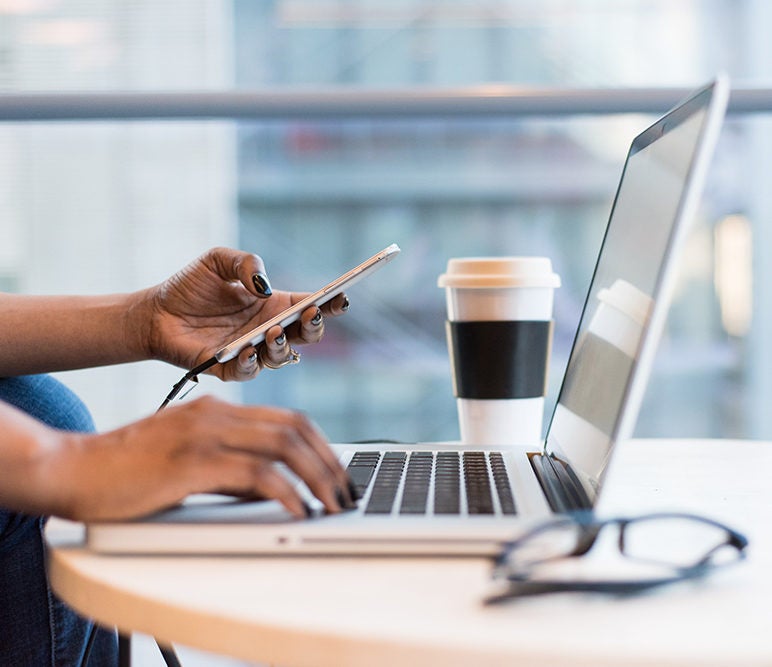 woman working on a laptop in the office and having a cup of coffee